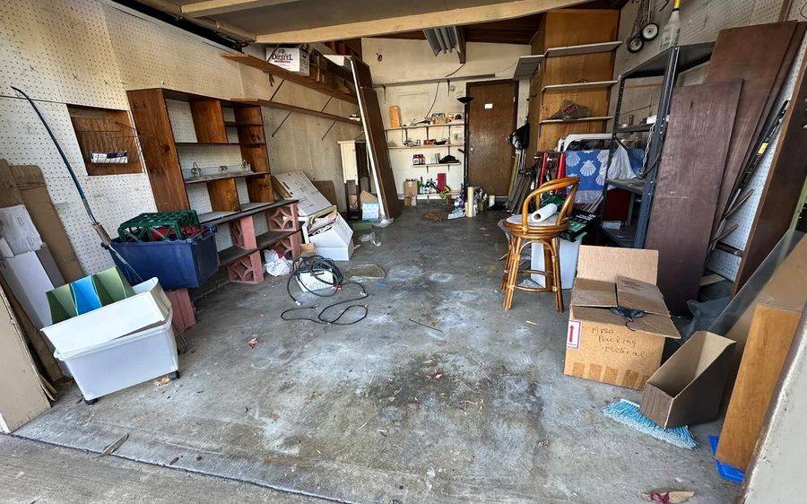 Cluttered garage with boxes and furniture before removal