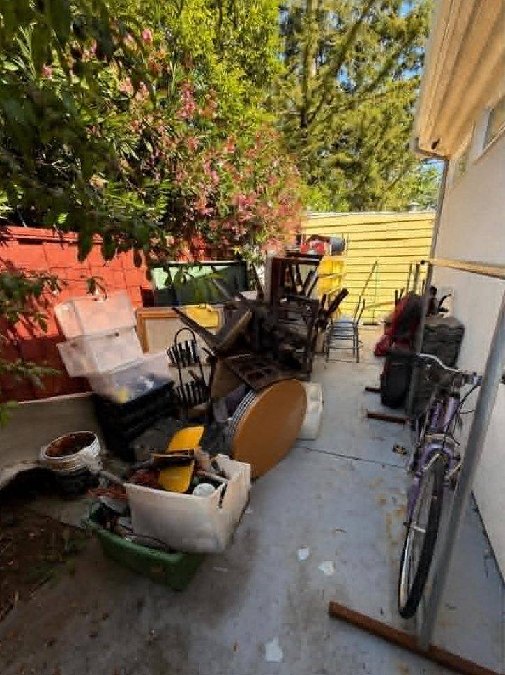 Patio crowded with furniture and bins before removal